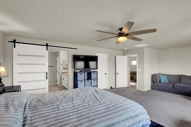 carpeted bedroom featuring ceiling fan, a barn door, and ensuite bathroom