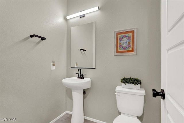 bathroom featuring baseboards and toilet