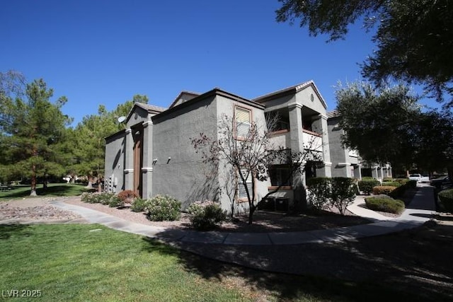 view of side of home with a lawn and stucco siding