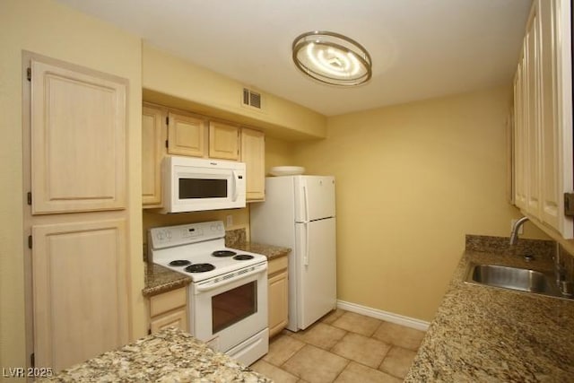 kitchen featuring light brown cabinets, white appliances, a sink, visible vents, and baseboards