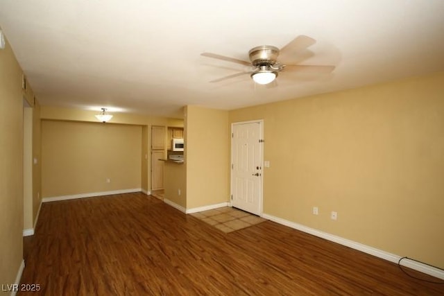 interior space with a ceiling fan, baseboards, and wood finished floors