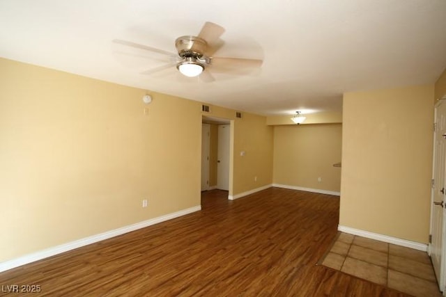 unfurnished room featuring a ceiling fan, visible vents, baseboards, and wood finished floors