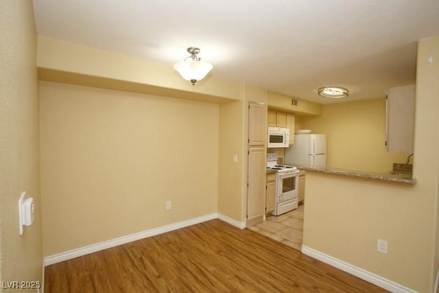 kitchen featuring white appliances, baseboards, a peninsula, light countertops, and light wood-style floors