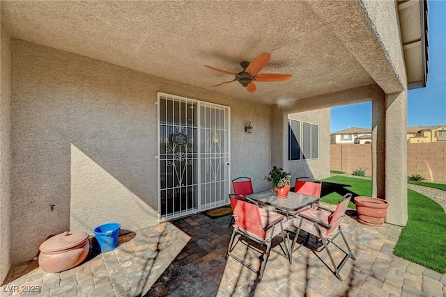 view of patio featuring fence, outdoor dining area, and a ceiling fan