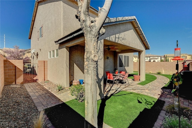 back of house featuring a patio area, a fenced backyard, a ceiling fan, and stucco siding