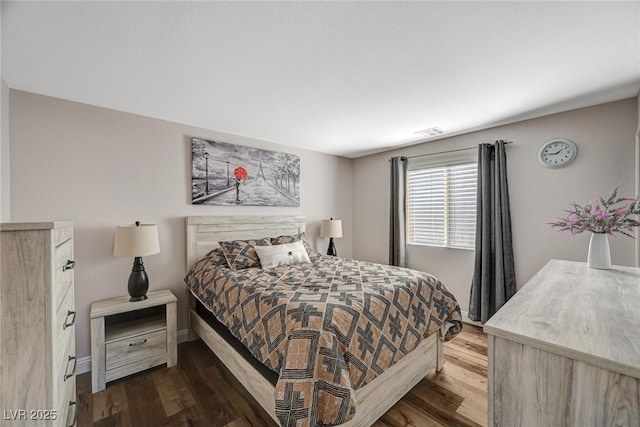 bedroom with wood finished floors, visible vents, and baseboards