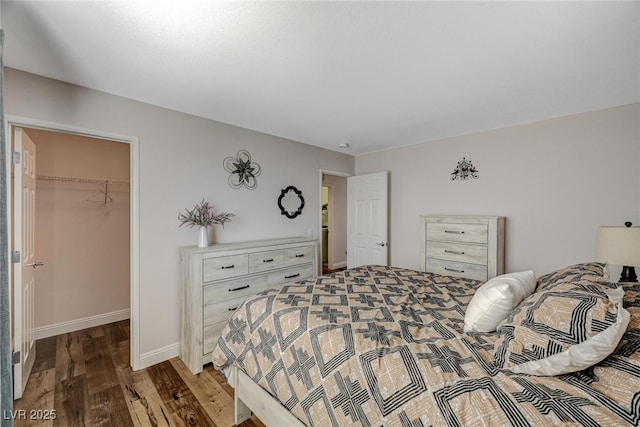 bedroom featuring a closet, baseboards, a walk in closet, and wood finished floors