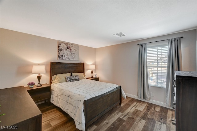 bedroom with visible vents, baseboards, and wood finished floors