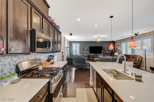 kitchen featuring stainless steel appliances, a sink, open floor plan, a wealth of natural light, and tasteful backsplash