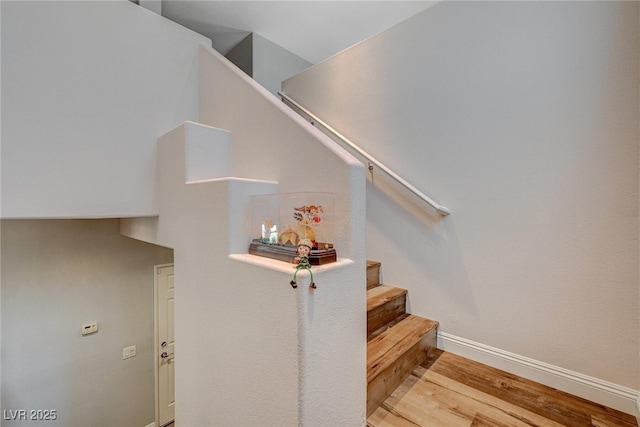 stairway with wood finished floors and baseboards