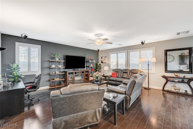 living area featuring dark wood-type flooring, plenty of natural light, visible vents, and baseboards