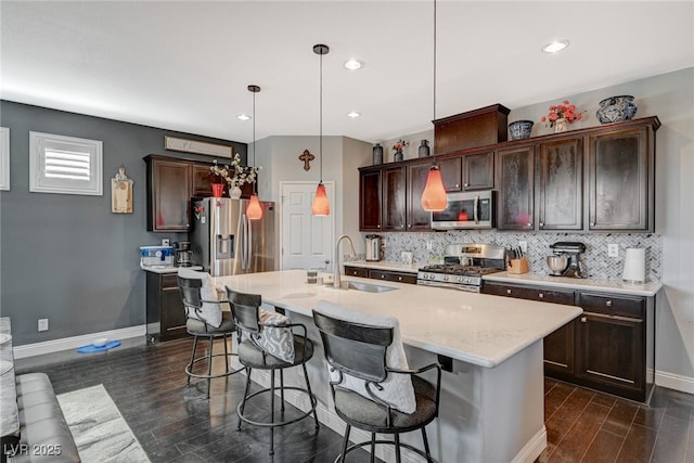 kitchen with a kitchen bar, appliances with stainless steel finishes, decorative backsplash, and a sink