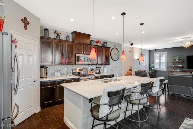 kitchen featuring dark wood-type flooring, a sink, open floor plan, appliances with stainless steel finishes, and decorative backsplash