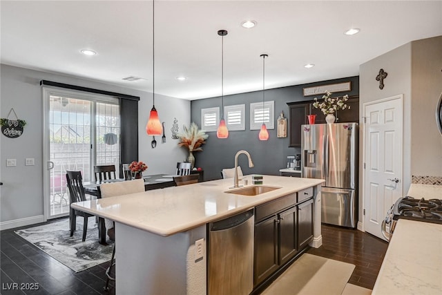 kitchen featuring stainless steel appliances, a sink, light countertops, dark wood-style floors, and pendant lighting