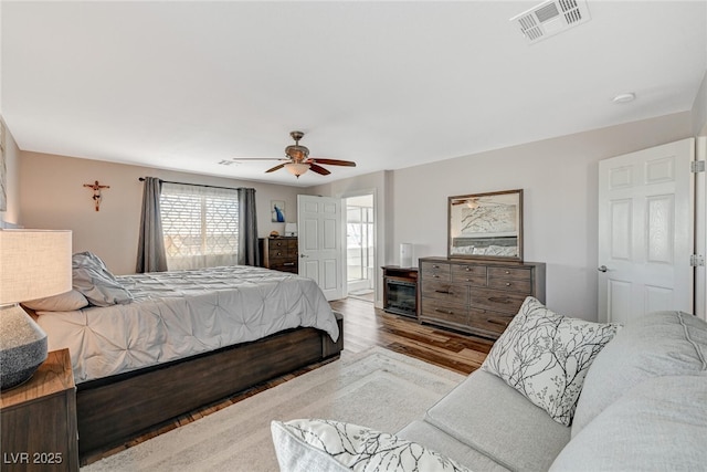 bedroom featuring a ceiling fan, visible vents, and wood finished floors