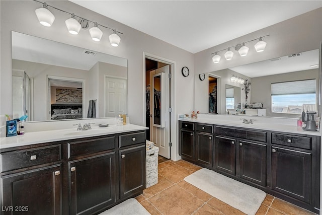 full bath with a sink, a spacious closet, two vanities, and visible vents