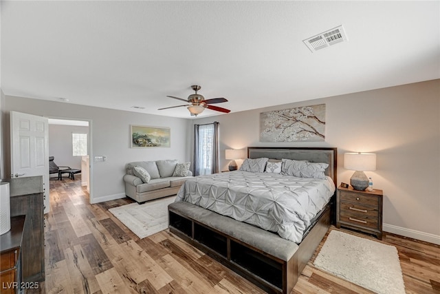 bedroom with baseboards, visible vents, multiple windows, and wood finished floors