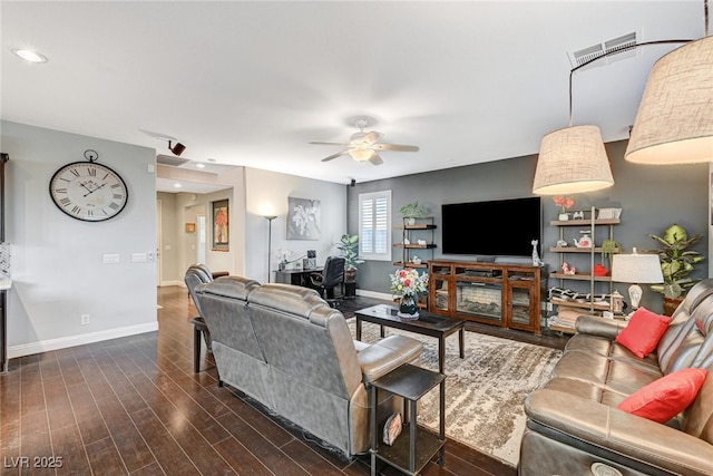 living area featuring a ceiling fan, visible vents, dark wood finished floors, and baseboards