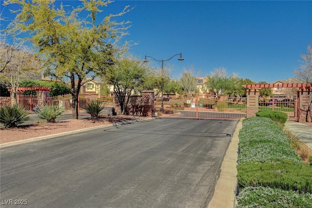 view of street with a gate, curbs, a gated entry, and street lights