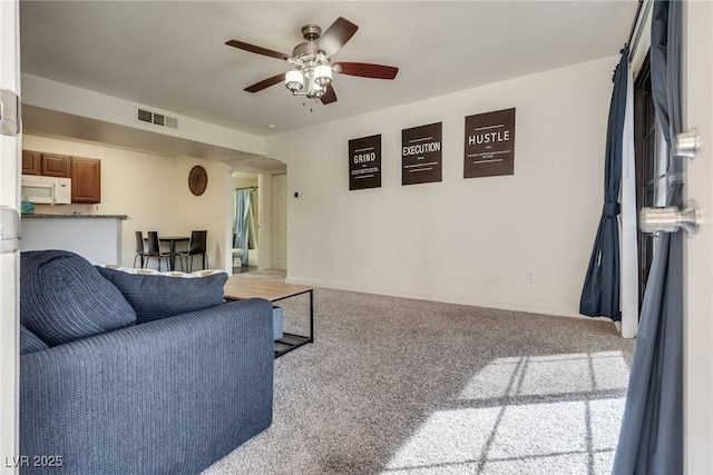 carpeted living room with a ceiling fan, arched walkways, visible vents, and baseboards