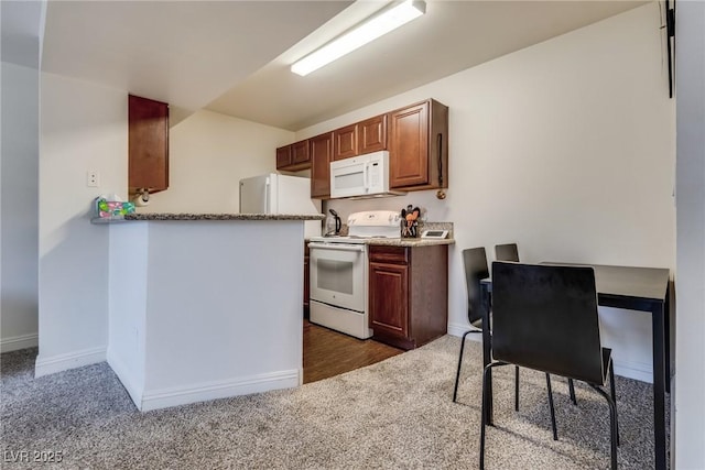 kitchen with a peninsula, white appliances, baseboards, and dark colored carpet