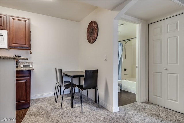 dining area featuring arched walkways, light carpet, and baseboards