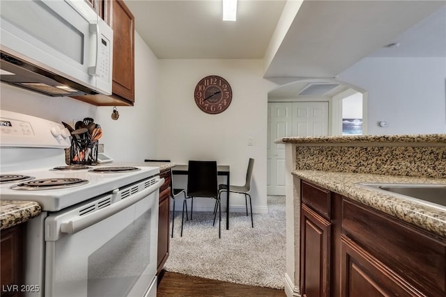 kitchen featuring white appliances, baseboards, and dark colored carpet