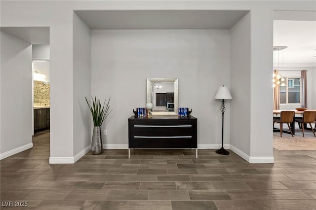 interior space featuring wood finish floors, a notable chandelier, and baseboards