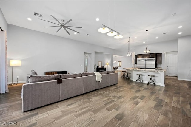 living area with recessed lighting, wood finished floors, a ceiling fan, baseboards, and visible vents