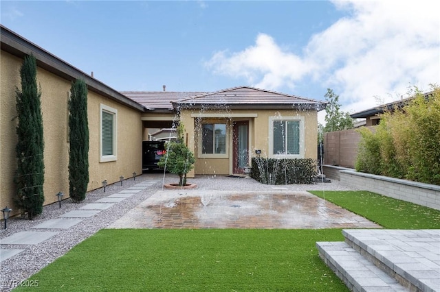 rear view of house featuring a patio area, fence, a lawn, and stucco siding