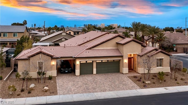 view of front of house with a garage, a tiled roof, decorative driveway, and stucco siding