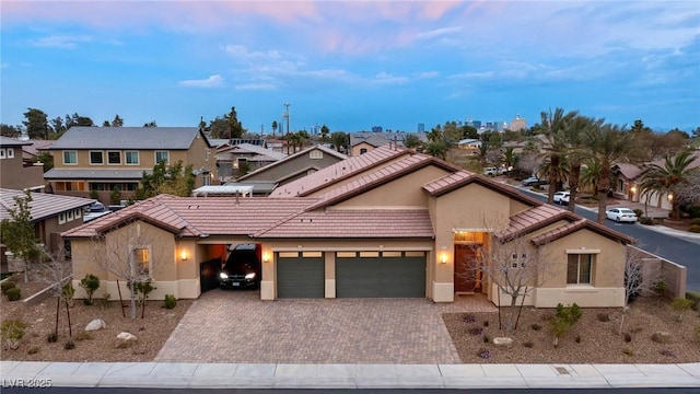 view of front facade with decorative driveway, stucco siding, a garage, a residential view, and a tiled roof