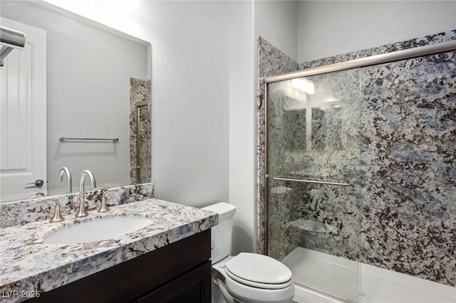 bathroom featuring toilet, a shower stall, and vanity