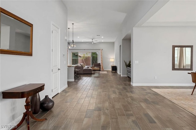 corridor with recessed lighting, dark wood-style flooring, a notable chandelier, and baseboards