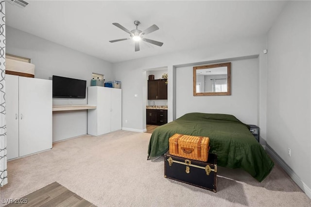 carpeted bedroom featuring ensuite bath, baseboards, visible vents, and ceiling fan