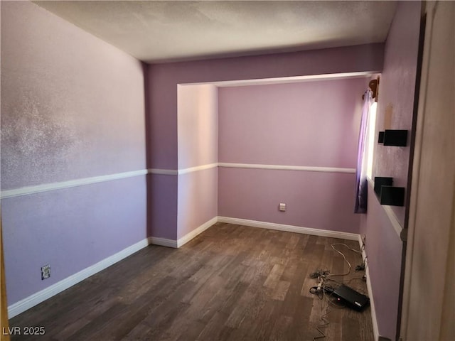 spare room featuring baseboards and wood finished floors