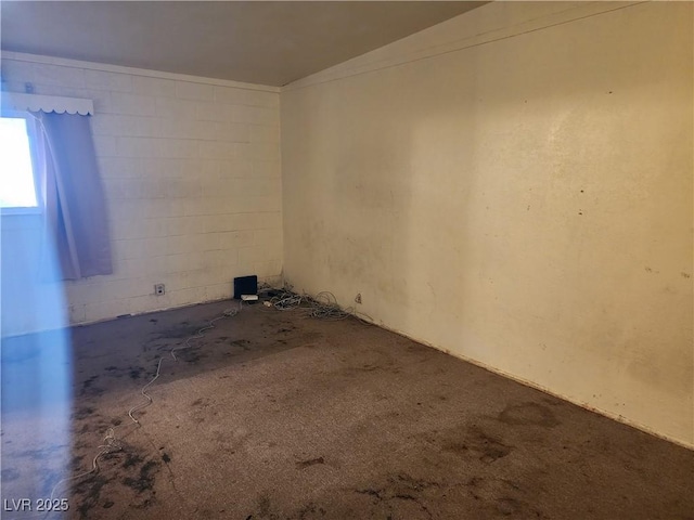 unfurnished room with unfinished concrete flooring and concrete block wall