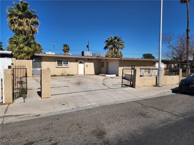 view of front of property with a garage, concrete driveway, a fenced front yard, a gate, and stucco siding