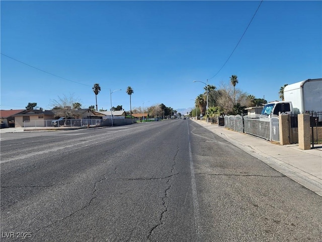 view of road with sidewalks, a residential view, curbs, and street lights