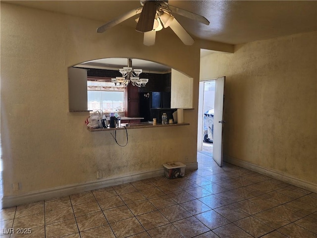 kitchen featuring tile patterned flooring, ceiling fan with notable chandelier, baseboards, and freestanding refrigerator