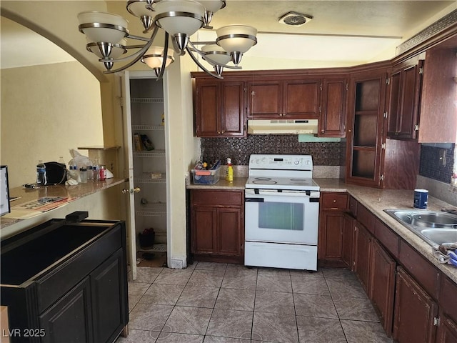 kitchen featuring a notable chandelier, white electric stove, light countertops, a sink, and under cabinet range hood