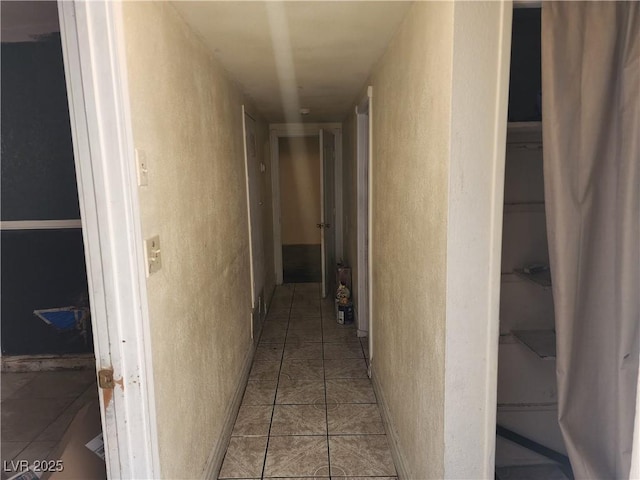 hall featuring tile patterned flooring and a textured wall