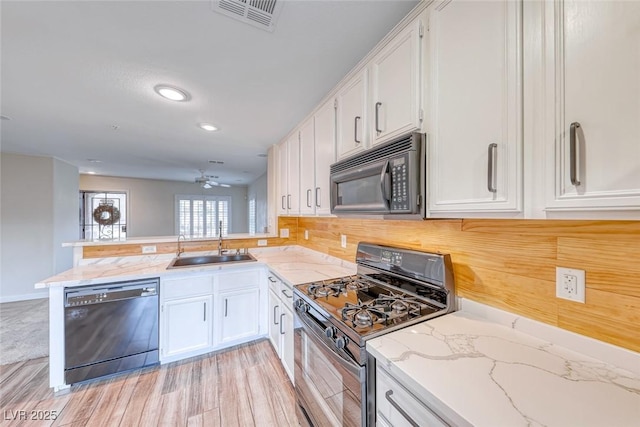 kitchen with visible vents, white cabinetry, a sink, a peninsula, and black appliances