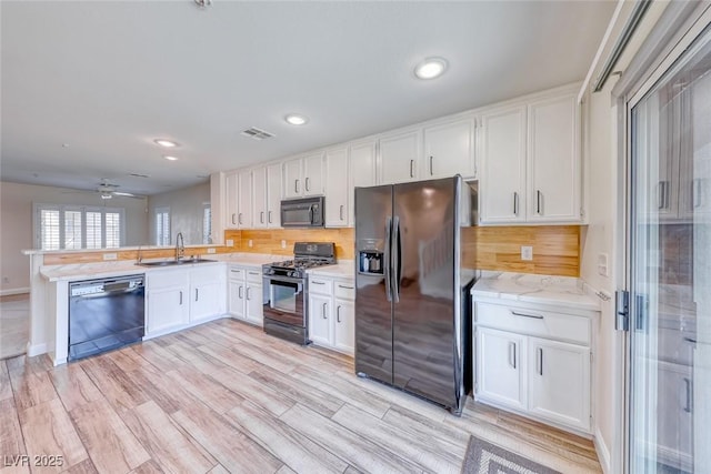 kitchen with visible vents, white cabinets, a sink, a peninsula, and black appliances