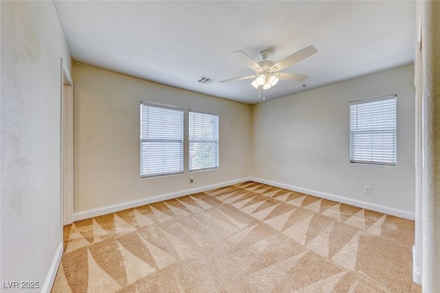 carpeted empty room featuring ceiling fan, visible vents, and baseboards