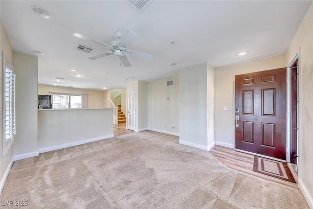 interior space with light carpet, baseboards, stairs, and visible vents