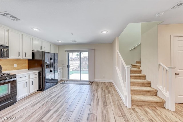 kitchen with black appliances, visible vents, light countertops, and light wood-style floors