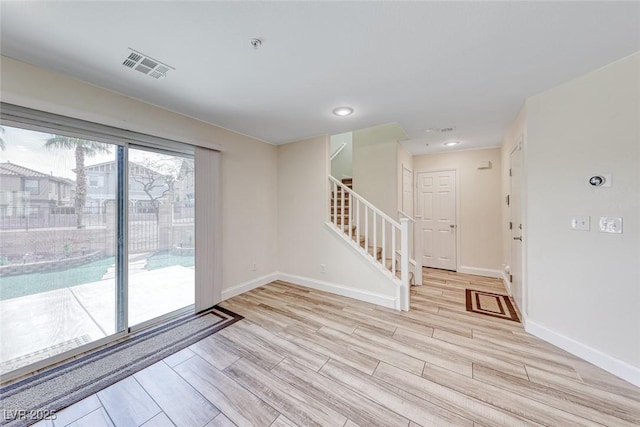 spare room featuring wood finish floors, visible vents, baseboards, and stairs