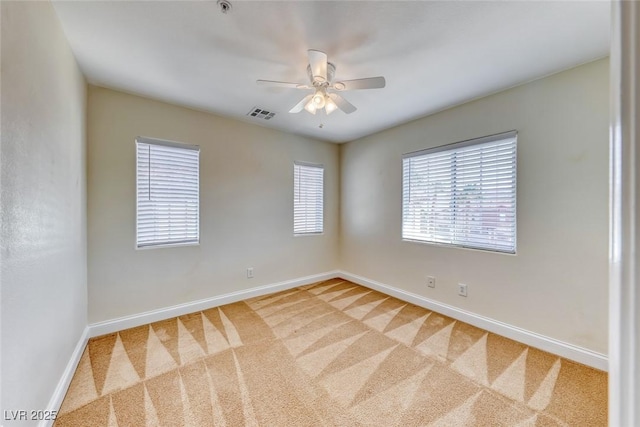 carpeted empty room featuring ceiling fan, a wealth of natural light, visible vents, and baseboards