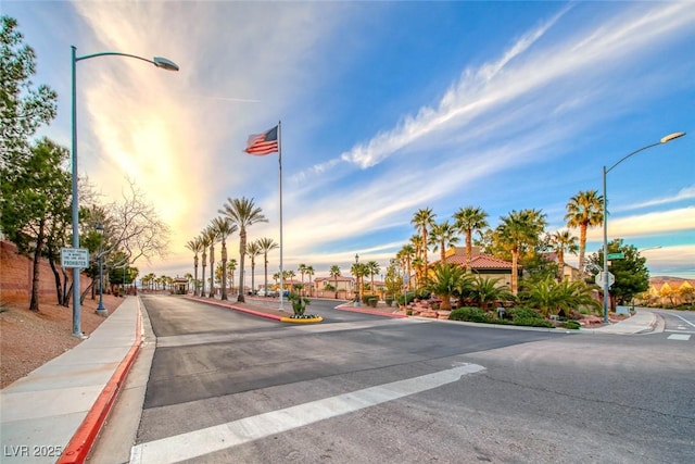 view of road featuring street lights, curbs, traffic signs, and sidewalks